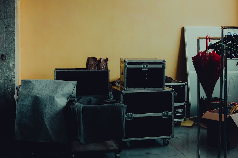 Many boxes and huge iron cases near umbrella placed in room with yellow walls